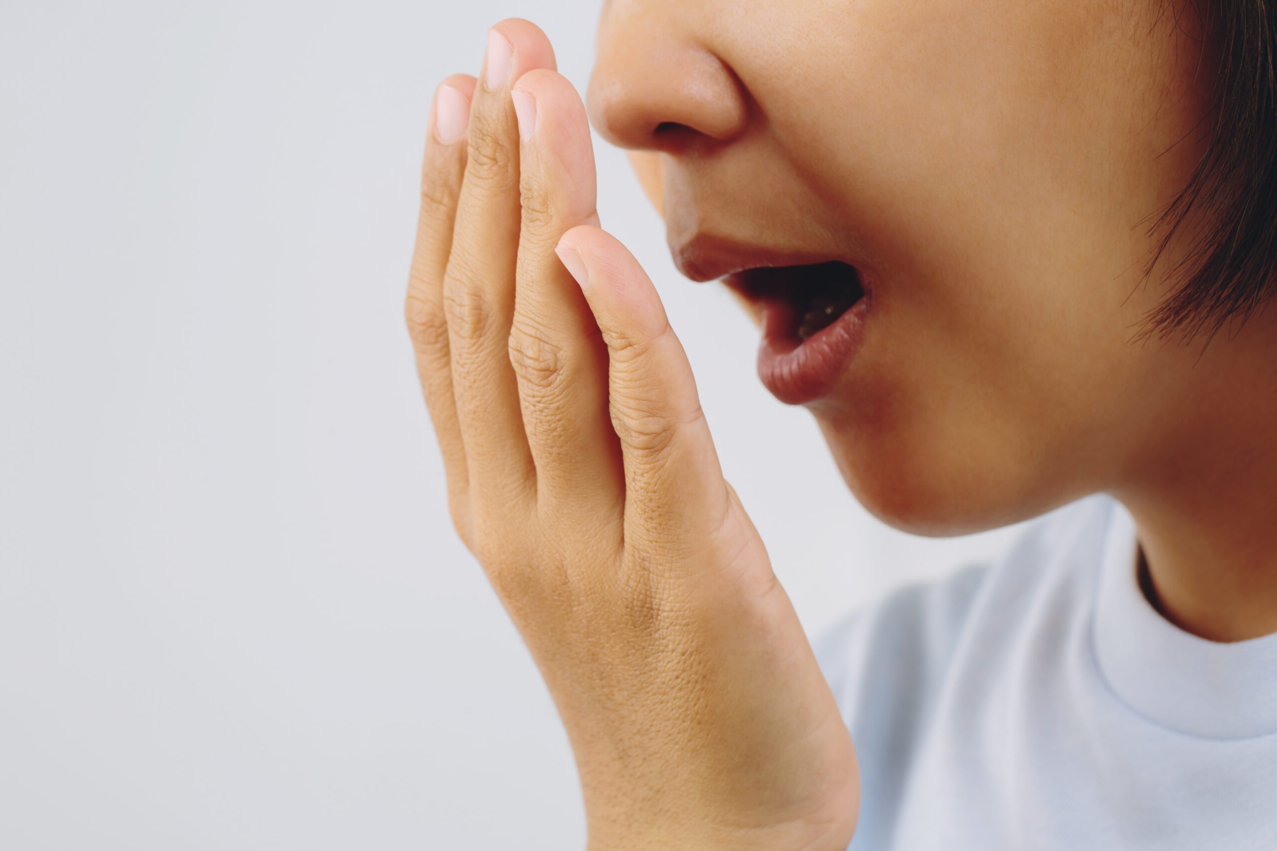 Asian woman checking her breath with hand test