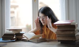 female-student-suffering-from-headache-in-library
