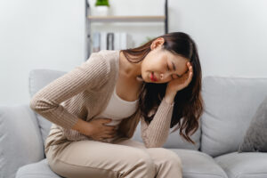 The woman with a stomachache is holding her stomach in pain