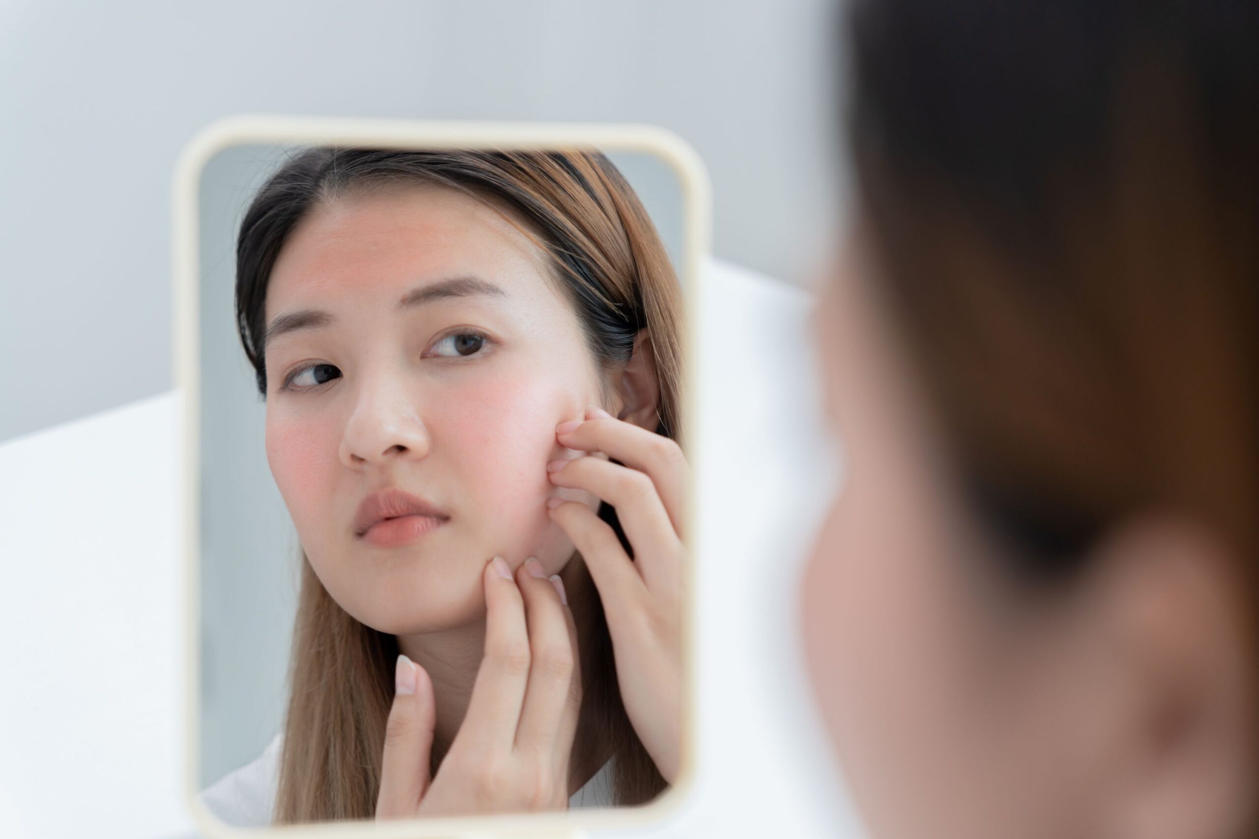 woman looking in mirror at her face
