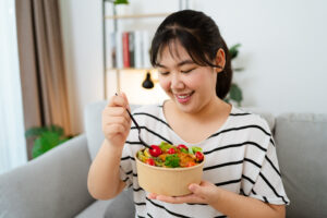 woman eating vegetable salad in paper cup