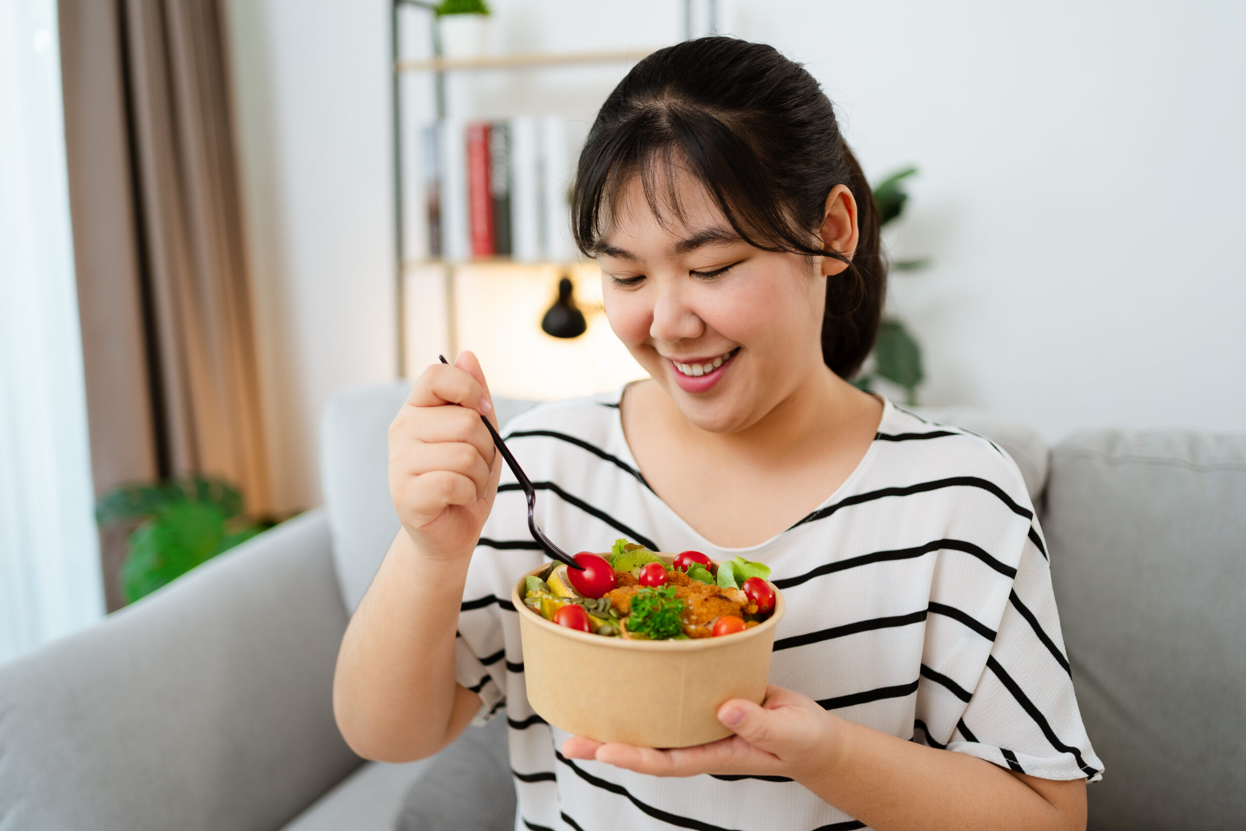woman eating vegetable salad in paper cup