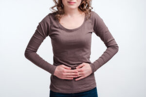 Young girl with abdominal pain close up, stomach pain clutching her stomach