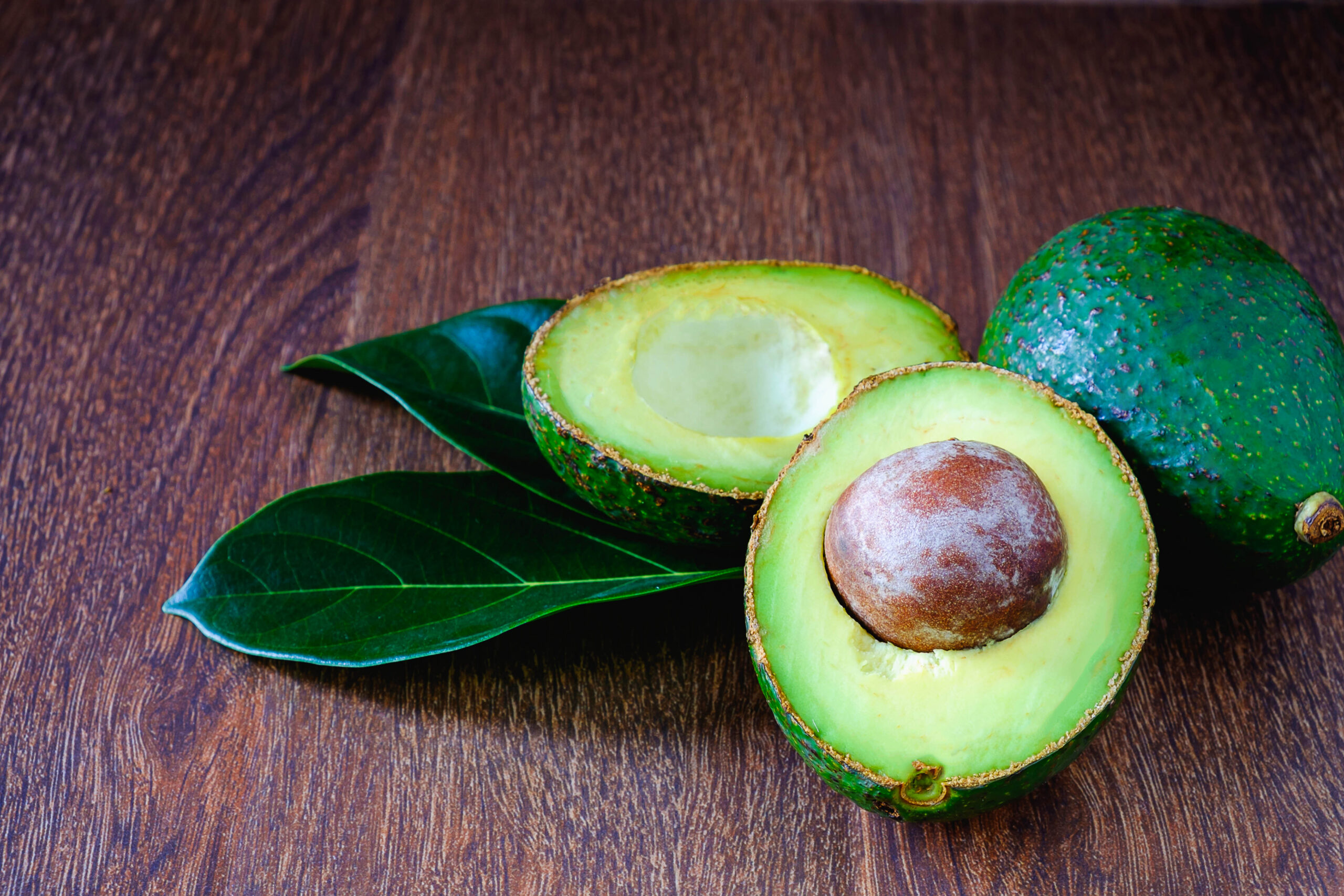 Avocado fruits and leaves on wooden boards